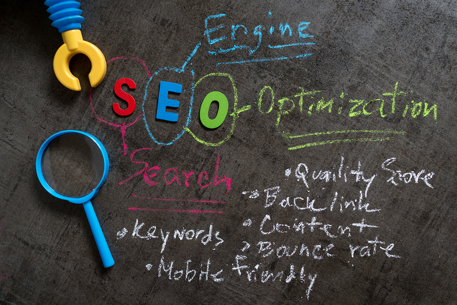 seo-search-engine-optimization-concept-as-colorful-alphabet-seo-handwriting-explanation-with-color-chalk-robot-arm-and-magnifying-glass-on-blackboard-wallpaper